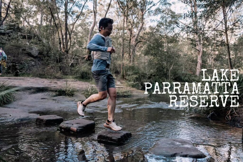 Tim Xu crossing creek on stepping stones during the Sydney Trail Half Marathon at Lake Parramatta Reserve.